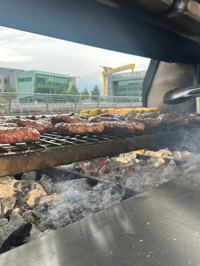 Burgers, sausages and corn on the cob cooking on the grill