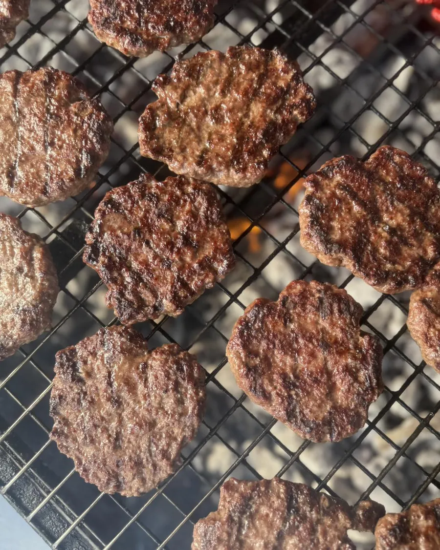 Flame-grilled burgers on a grill rack