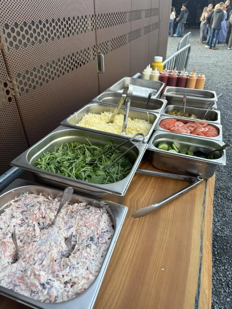 Outdoor salad bar with coleslaw, rocket, cheese and sauces