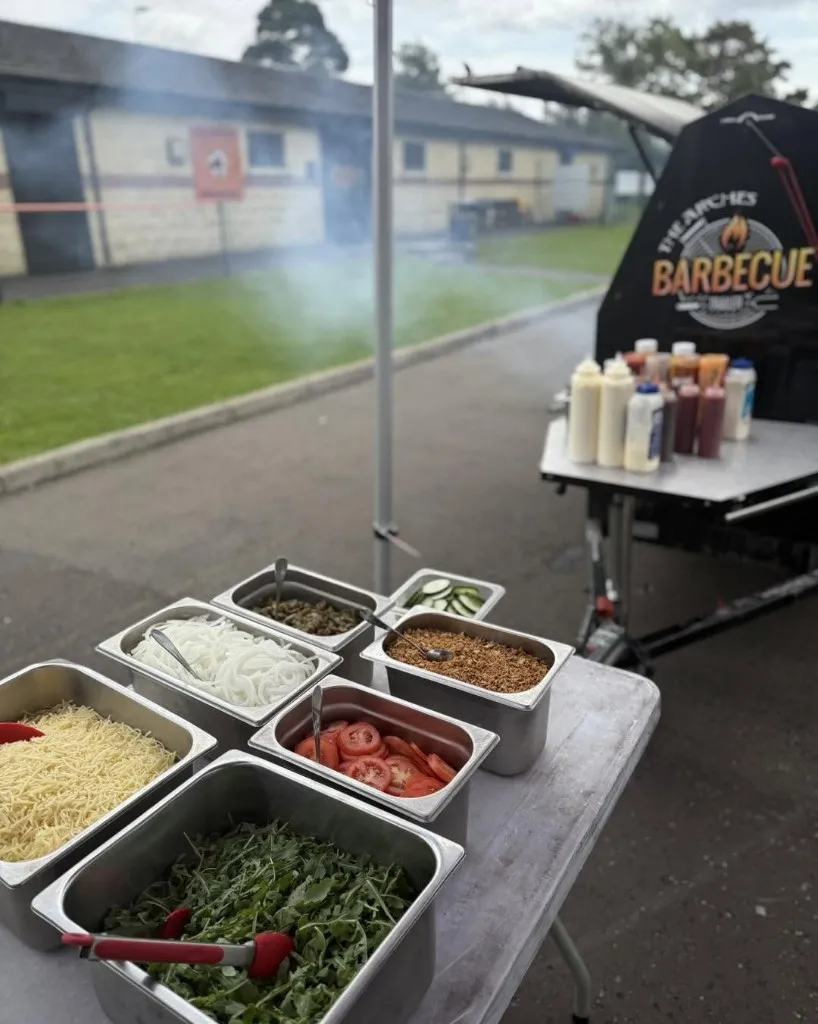 Fresh salad and burger toppings station beside the BBQ trailer